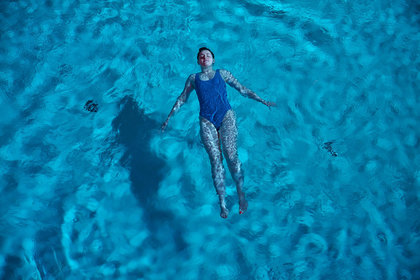 Junge Frau treibt auf dem Rücken im Pool