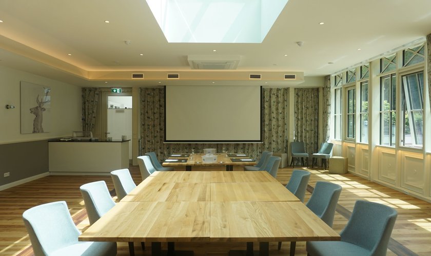 A room flooded with light through a skylight, furnished with tables for a workshop.