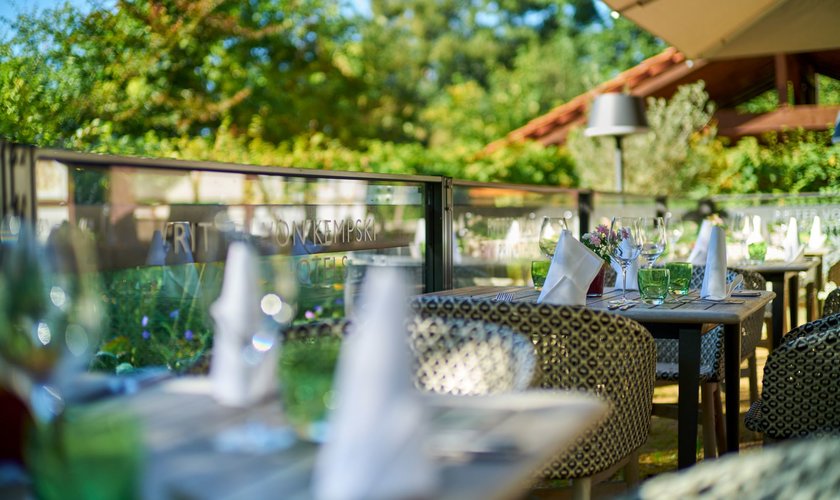 Elegantly laid tables in the foreground on the terrace of the Jagdhaus Holzeule.